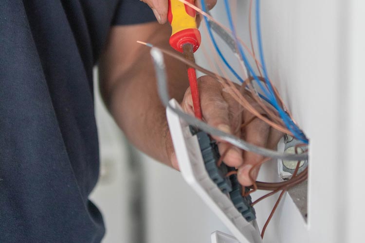 En ung kvinna med blont hår arbetar med elinstallation inomhus